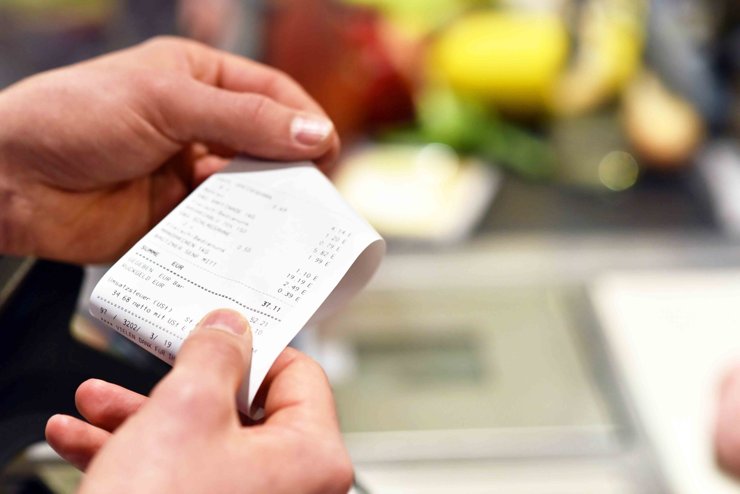 Hände mit Kassenzettel an der Kasse im Supermarkt